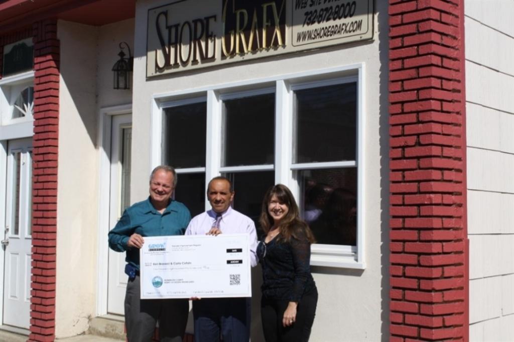 ShoreGarfx owners Ken Braswell and Carla Cefalo accepted a $1,850 Façade Improvement Program reimbursement check from Freeholder Thomas A. Arnone (center) on Oct. 3 in Highlands, NJ.